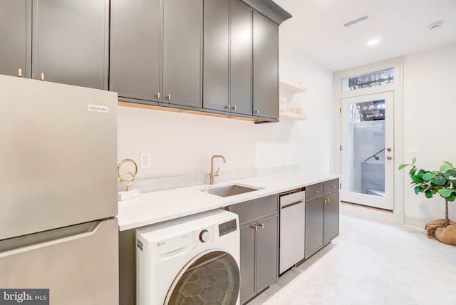 clothes washing area with light tile patterned floors, washer / clothes dryer, and sink