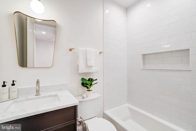 full bathroom featuring tiled shower / bath, vanity, and toilet