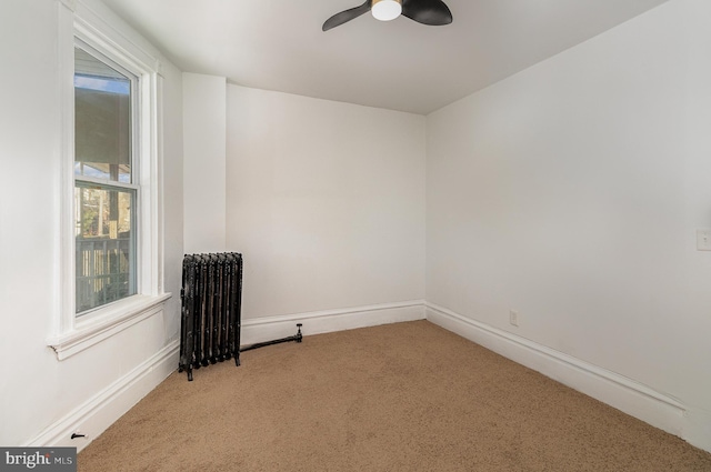 spare room featuring ceiling fan, light carpet, and radiator