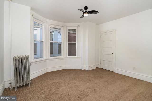 carpeted spare room featuring radiator and ceiling fan