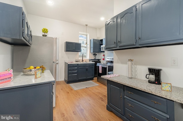 kitchen featuring decorative light fixtures, light hardwood / wood-style floors, stainless steel range with electric cooktop, and sink