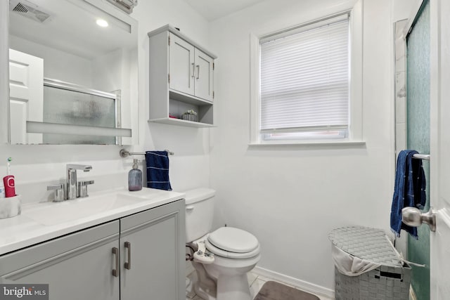 bathroom featuring vanity, a shower with shower door, and toilet