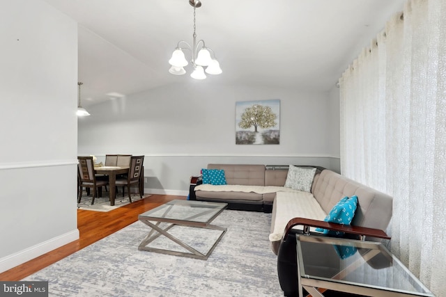 living room with vaulted ceiling, a chandelier, and hardwood / wood-style floors