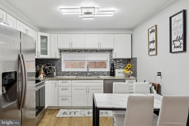 kitchen featuring sink, light hardwood / wood-style flooring, appliances with stainless steel finishes, light stone counters, and white cabinets