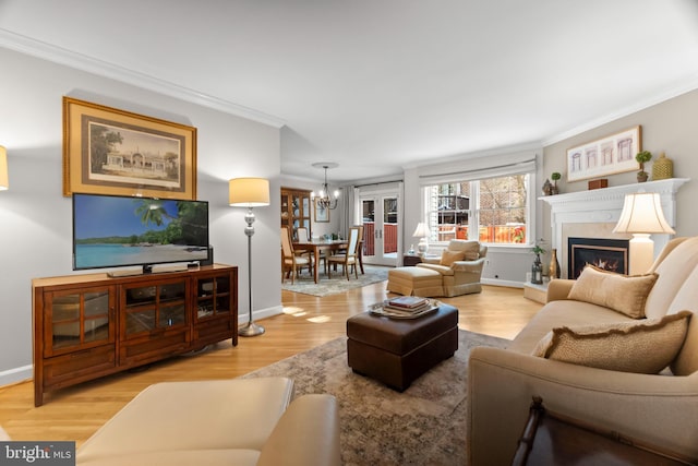 living room with crown molding, a fireplace, wood-type flooring, and an inviting chandelier