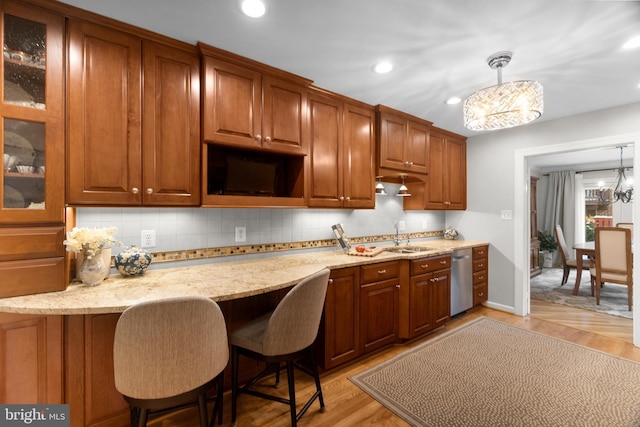 kitchen with a chandelier, light stone counters, hanging light fixtures, and light hardwood / wood-style flooring