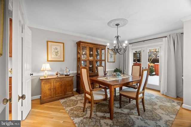 dining room featuring french doors, light hardwood / wood-style floors, crown molding, and a notable chandelier