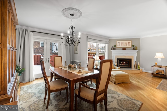 dining room featuring hardwood / wood-style flooring, a notable chandelier, ornamental molding, and a fireplace