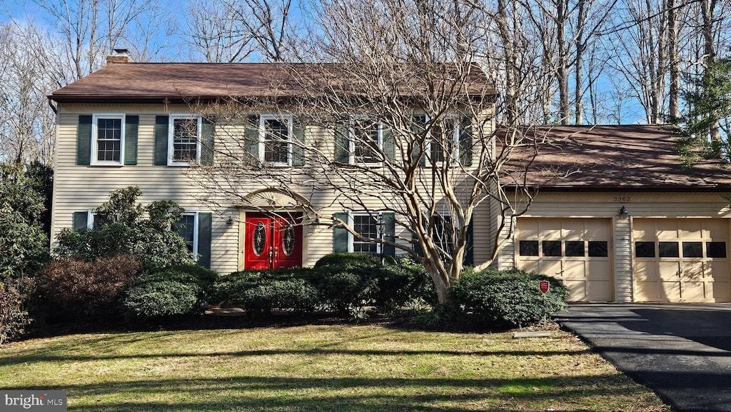 colonial house with a garage and a front lawn