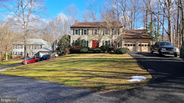 colonial inspired home with a garage and a front yard