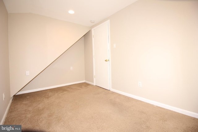 empty room featuring lofted ceiling, recessed lighting, light colored carpet, and baseboards