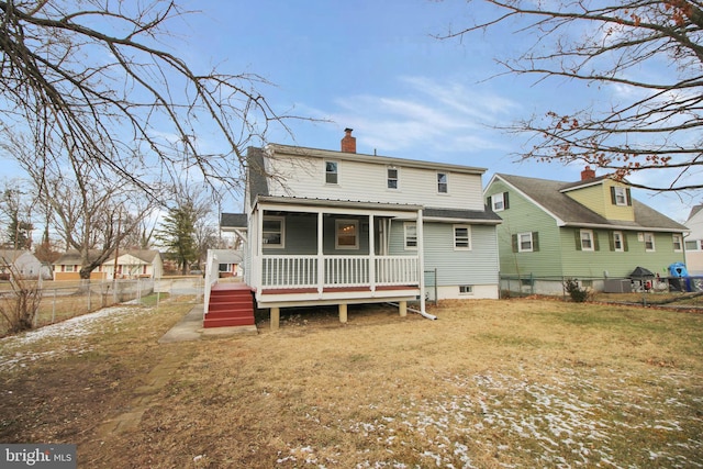 rear view of property with a yard, a chimney, and fence