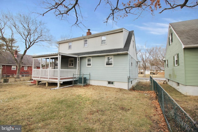 rear view of house with a fenced backyard, a yard, roof with shingles, a wooden deck, and a chimney