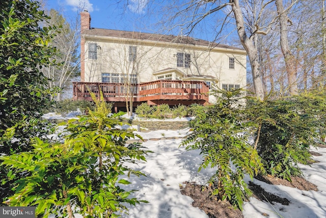 snow covered back of property with a deck