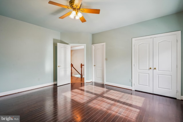 unfurnished bedroom featuring dark wood-type flooring, ceiling fan, and a closet