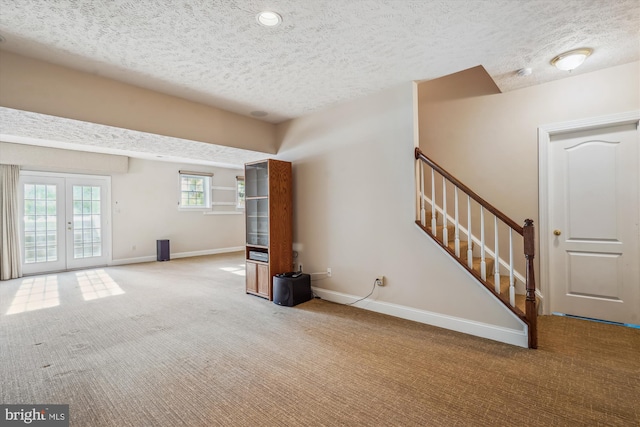 unfurnished living room with carpet, a textured ceiling, and french doors