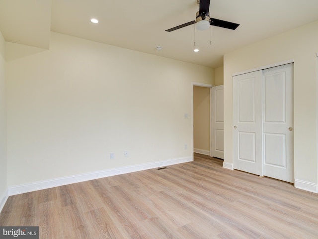 unfurnished bedroom with ceiling fan, light wood-type flooring, and a closet