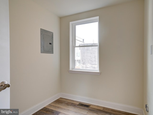 empty room with hardwood / wood-style floors and electric panel