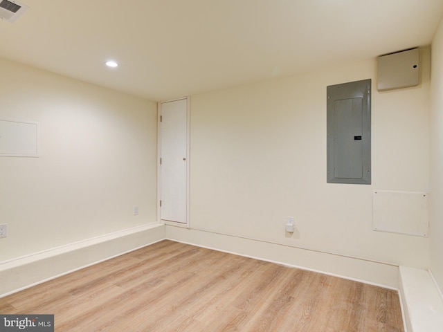 spare room with electric panel and light hardwood / wood-style flooring