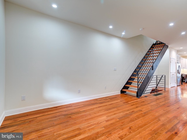 basement featuring stainless steel fridge and light hardwood / wood-style floors