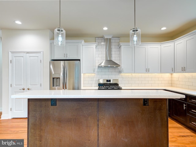 kitchen with wall chimney exhaust hood, a center island, white cabinetry, and stainless steel appliances