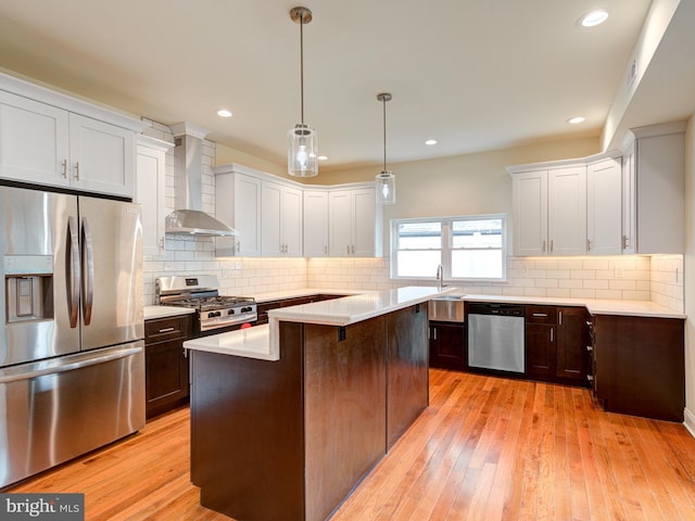 kitchen with a center island, white cabinets, wall chimney range hood, and appliances with stainless steel finishes