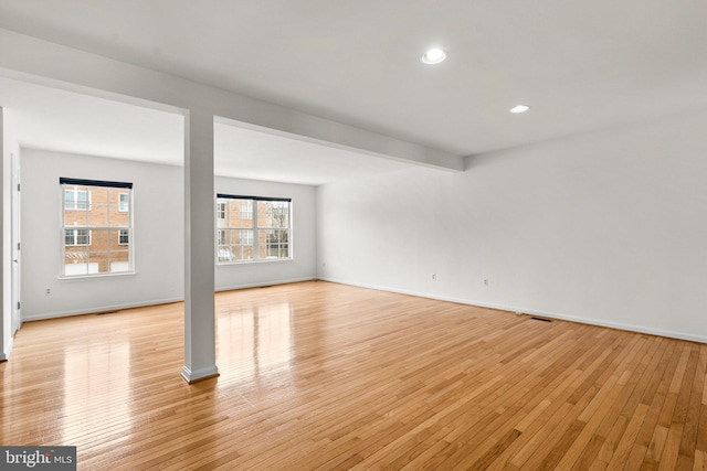 spare room with beamed ceiling and light wood-type flooring