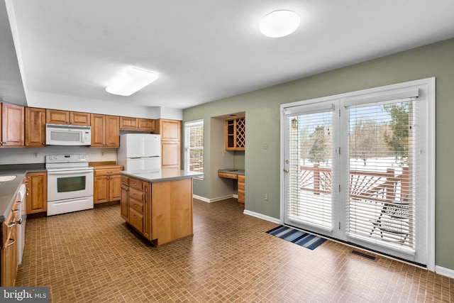 kitchen with built in desk, a center island, and white appliances