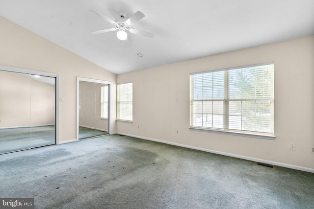 unfurnished bedroom with ceiling fan, multiple windows, and multiple closets