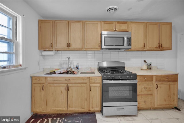 kitchen featuring decorative backsplash, sink, stainless steel appliances, and light brown cabinetry