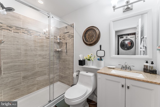 bathroom featuring a shower with shower door, toilet, vanity, and stacked washing maching and dryer