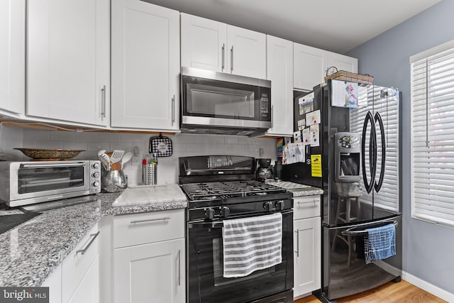 kitchen featuring light hardwood / wood-style floors, white cabinets, and black appliances