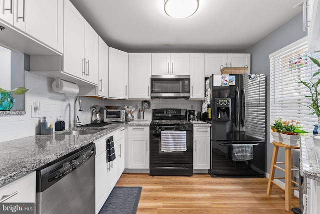 kitchen with white cabinets, black appliances, decorative backsplash, sink, and light hardwood / wood-style flooring