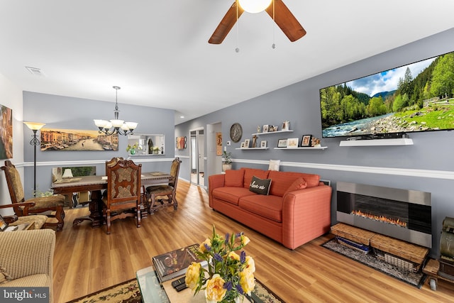 living room with heating unit, wood-type flooring, and ceiling fan with notable chandelier