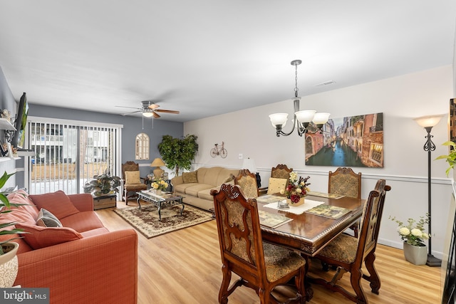 dining area with ceiling fan with notable chandelier and wood-type flooring