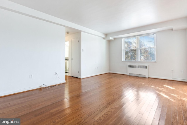 unfurnished room with light hardwood / wood-style floors and radiator heating unit