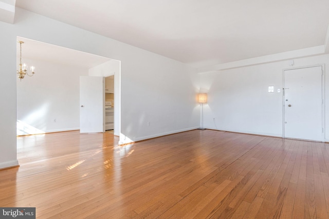 spare room featuring light hardwood / wood-style floors and a chandelier