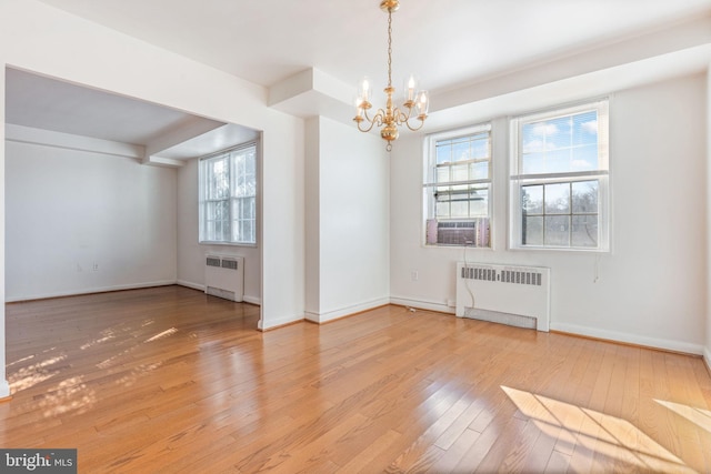 unfurnished dining area with an inviting chandelier, wood-type flooring, cooling unit, and radiator heating unit