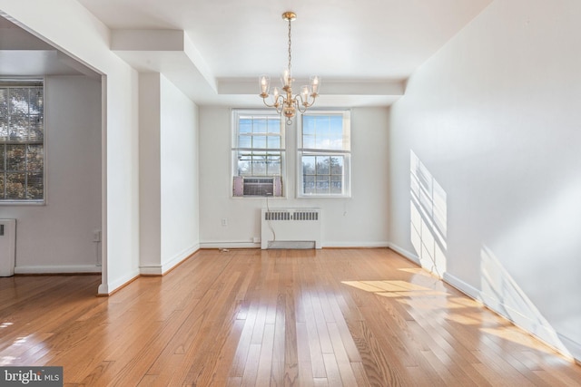 unfurnished dining area featuring radiator, wood-type flooring, and a chandelier