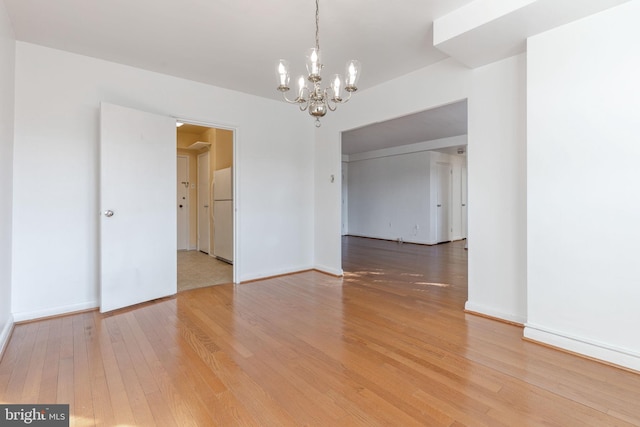 spare room with hardwood / wood-style flooring and a notable chandelier