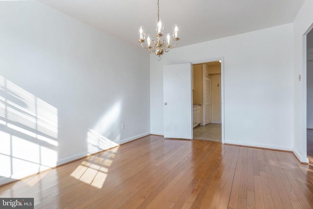 unfurnished room featuring a notable chandelier and light hardwood / wood-style flooring