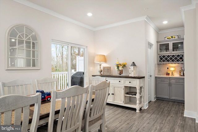 dining space with crown molding, hardwood / wood-style floors, and indoor bar