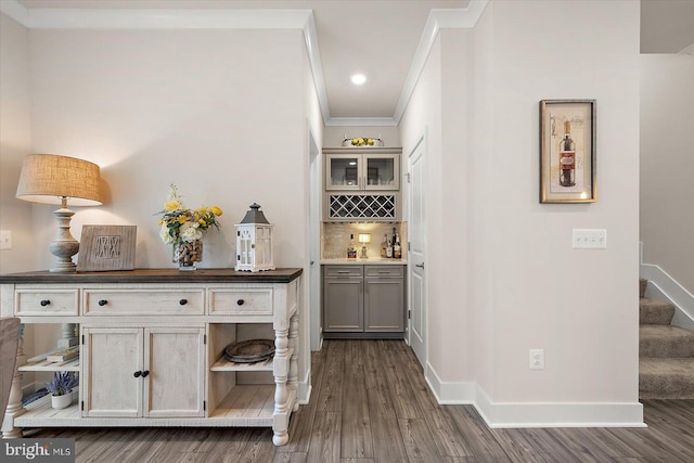 bar with dark hardwood / wood-style flooring, ornamental molding, and gray cabinetry