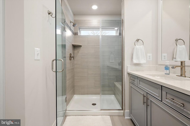 bathroom featuring a shower with door and vanity