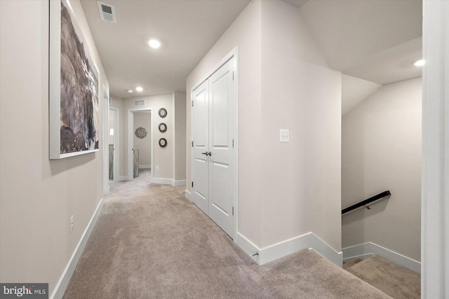 hallway with light colored carpet and lofted ceiling