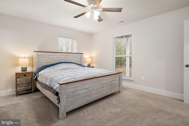 bedroom with multiple windows, light colored carpet, and ceiling fan