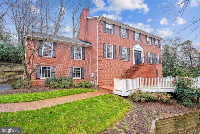 colonial inspired home featuring a deck and a front lawn