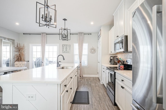 kitchen featuring sink, pendant lighting, a center island with sink, white cabinets, and appliances with stainless steel finishes