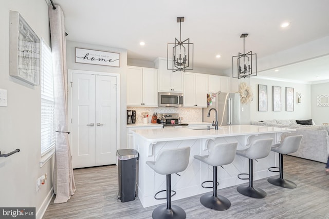 kitchen featuring hanging light fixtures, a kitchen breakfast bar, stainless steel appliances, and a kitchen island with sink