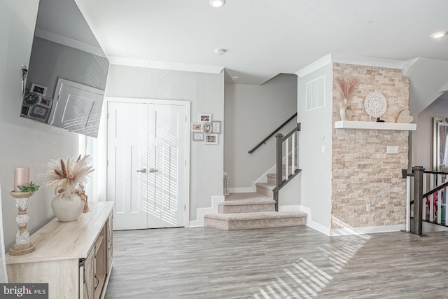 foyer entrance featuring crown molding and light hardwood / wood-style flooring